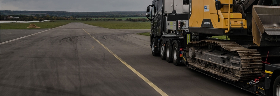 Caminhão em estrada transportando máquina pesada da Volvo