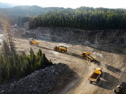 Volvo articulated hauler trucks rolling in line in a harsh environment.