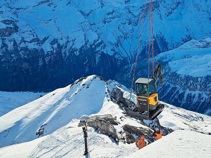Elektrisk gravemaskin som arbeider innenfor rekreasjon på et skianlegg